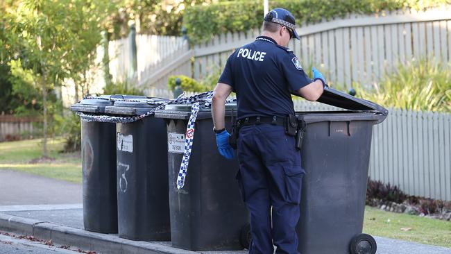 A policeman searches bins near where a woman’s body was found in Toowong. Pic: Jack Tran