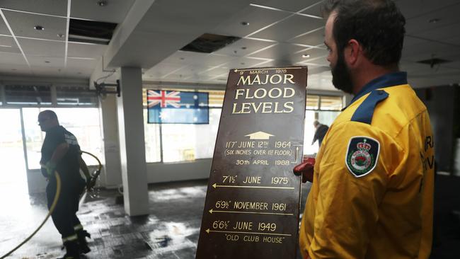 A month later on April 8, Camden West RFS brigade member Chris Patterson looks at previous flood levels while helping to clean up yet more floodwater.