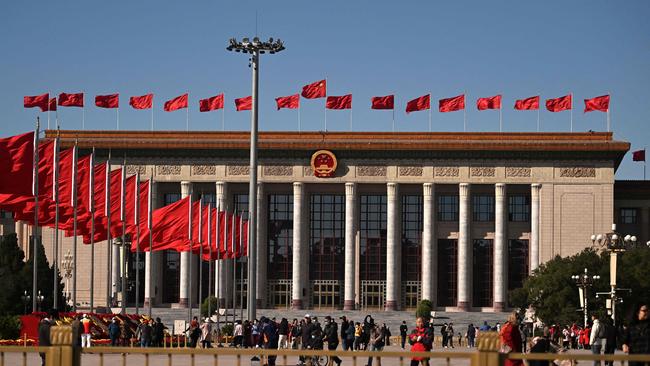 People walk before the Great Hall of the People at Tiananmen Square ahead of the 20th Communist Party Congress in Beijing on October 10, 2022. (Photo by Noel Celis / AFP)