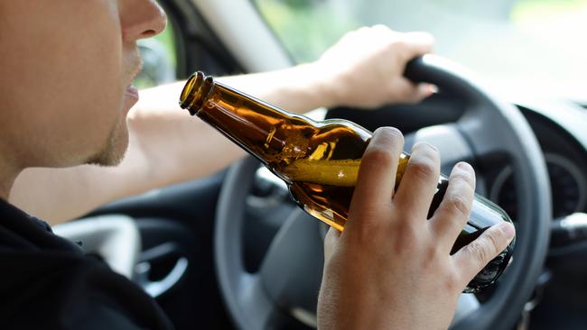 The concept of alcohol driving crime - closeup of young male driver hands with steering wheel and bottle of beer. Drink driving generic. Picture: iSTOCK