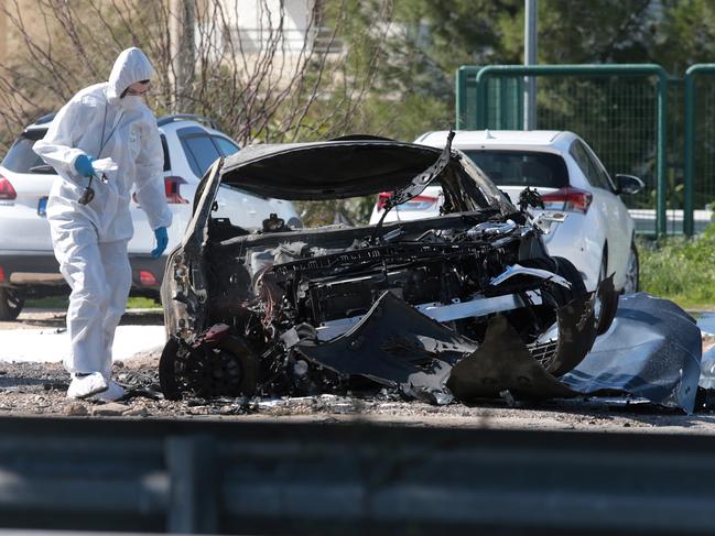 Police experts search for evidence at the site of an explosion at an open-air parking lot in the seaside suburb of Glyfada in Athens in 2019.