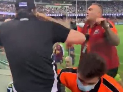 A Collingwood fan is restrained as he absues the umpires after Collingwood's loss to Brisbane.