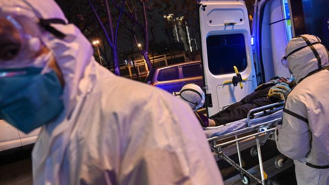 Medical staff wearing protective clothing to protect against a previously unknown coronavirus arrive with a patient at the Wuhan Red Cross Hospital in Wuhan. (Photo by Hector RETAMAL / AFP)