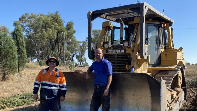 Graeme Morley and Tom Warren standing in front of the dozer.