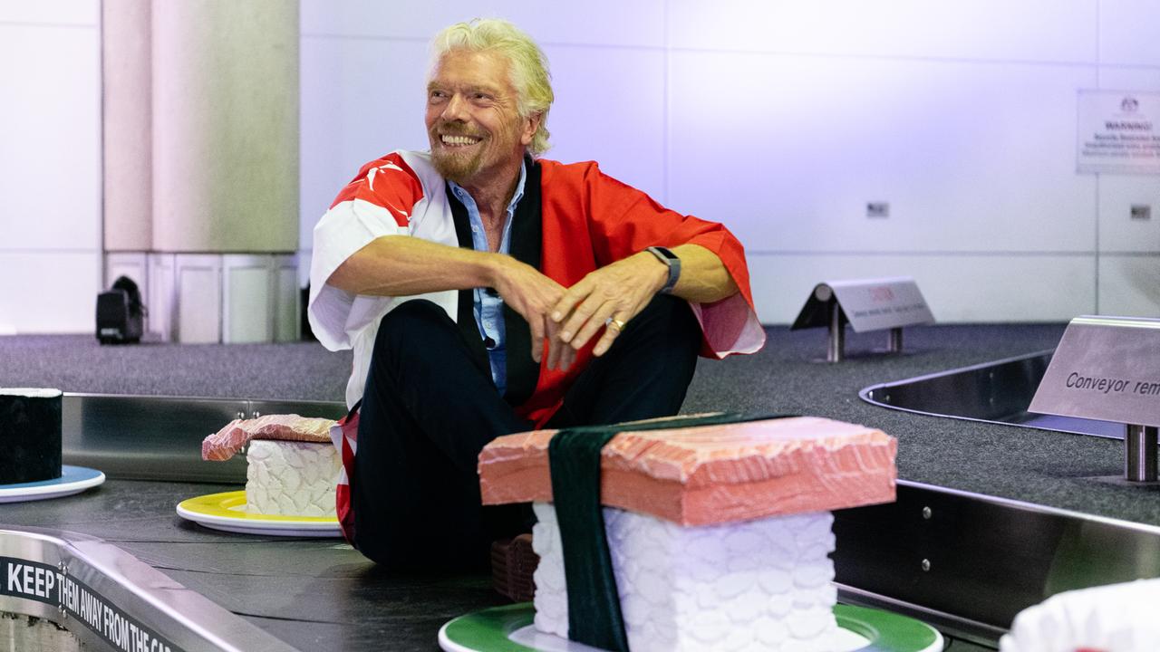 Sir Richard Branson takes a ride on a baggage carousel at Brisbane Airport. Picture: Virgin Australia