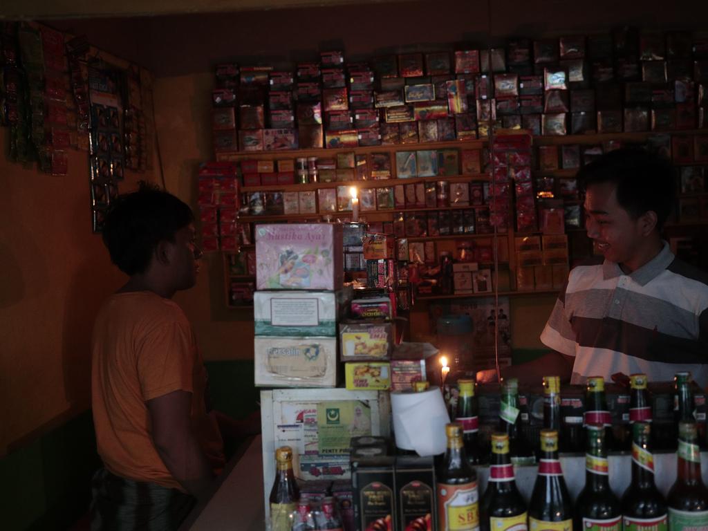 Women packages crackers beside candles because of power outage in southern  Jakarta, Indonesia, May