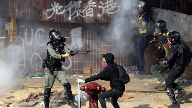 A policeman in riot gear points his weapon as protesters try to flee from the Hong Kong Polytechnic University in Hong Kong on Monday.