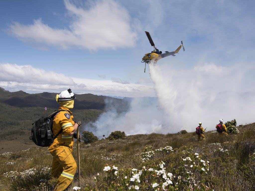 Parks and TFS firefighters watch for a waterbombing aircraft to strafe the fire edge before smothering the burnt remains with beaters/ hand tools. Picture: WARREN FREY / TASMANIA FIRE SERVICE