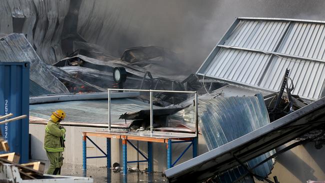 A firefighter at the Culture Kings warehouse at Acacia Ridge after it was destroyed in a blaze on Sunday.