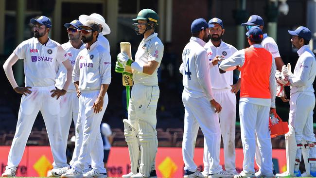 Indian players along with Australia's captain Tim Paine wait while fans are ejected from the SCG for alleged abuse of Indian bowler Mohammed Siraj Picture: AFP