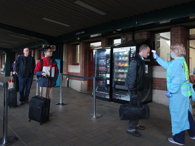 A nurse takes the temperature of a rail passenger arriving at Central Station from Melbourne. Picture: Getty Images