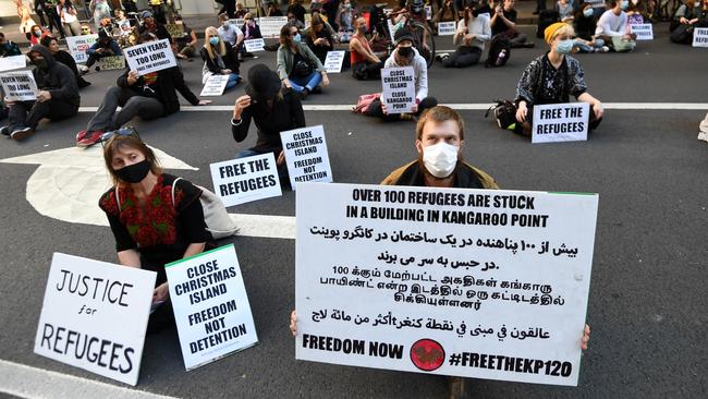 Protesters sit outside the Department of Immigration building during a march through central Brisbane. Picture: NCA NewWire/Dan Peled)