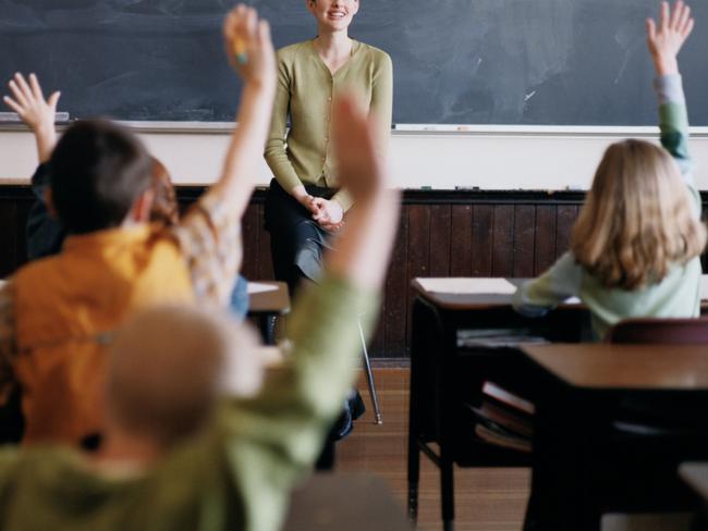 Generic pic of a teacher standing at the blackboard while talking to students in a classroom.