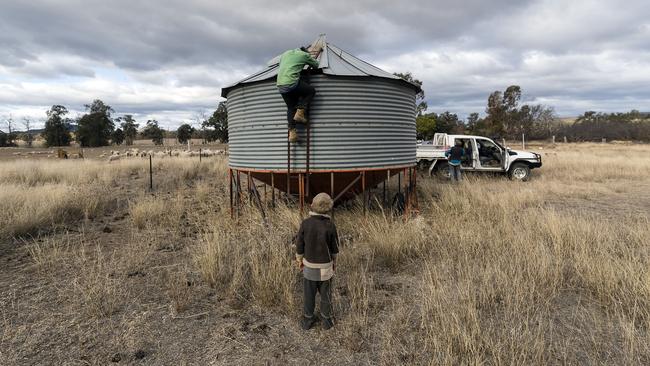 Harry watches his dad check a tank. The Coonabarabran dam is down to just 23 per cent capacity, forcing residents to live with level six water restrictions. Picture: Getty