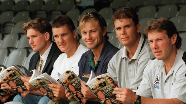 James Hird, Glen Jakovich, Tony Modra, Wayne Carey and Gavin Brown reading the AFL players centenary season diary in the Great Southern stand of the MCG.