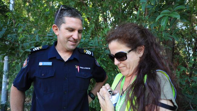 Queensland Fire Service officer Tim Walker assists Deanne Hall with the rescue of a baby duckling that fell into a storm water drain. Photo: Scott Powick