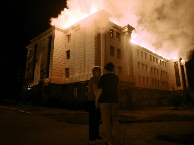 Bystanders watch a fire consuming a school in downtown Donetsk yesterday after being hit by shelling. Picture: Francisco Leong