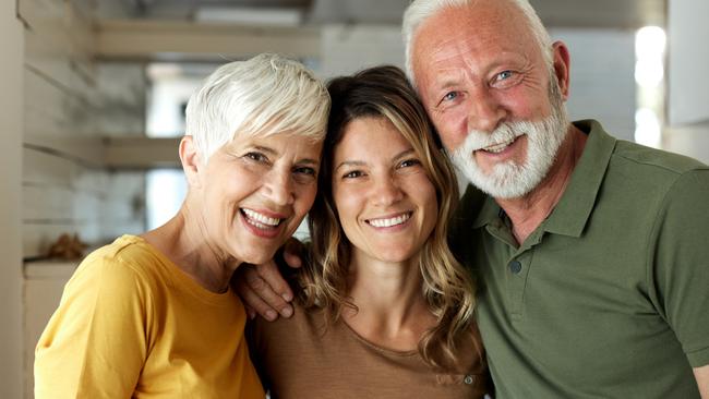 Happy adult daughter enjoying with her mature parents at home and looking at camera; Bank of Mum and Dad generic money