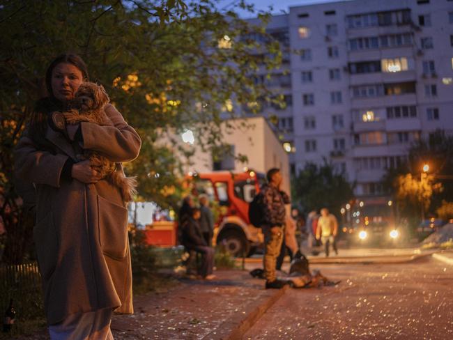 A woman walks amid shattered glass carrying her dog after her apartment building suffered damage in a Russian drone attack. Picture: Alex Babenko / AP