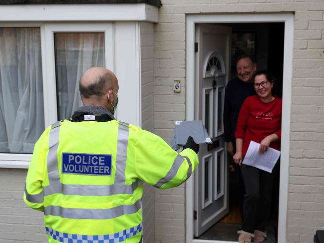 A police volunteer distributes coronavirus testing kits to residents in Woking in Surrey. Picture: AFP.