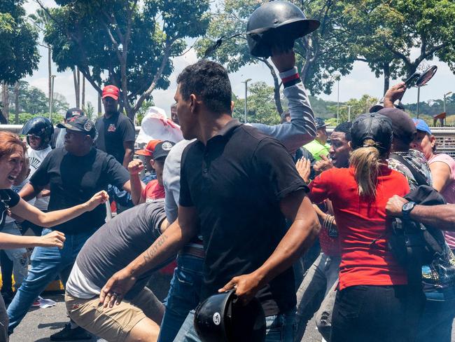 TOPSHOT - Opponents of the Venezuelan government clash against supporters of Venezuela's President Nicolas Maduro during a May Day (Labour Day) rally to mark the international day of the workers in Caracas on May 1, 2024. (Photo by Ivan Reyes / AFP)