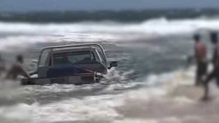 Footage shows beachgoers rush to remove the Ute from the lagoon on Bribie Island.