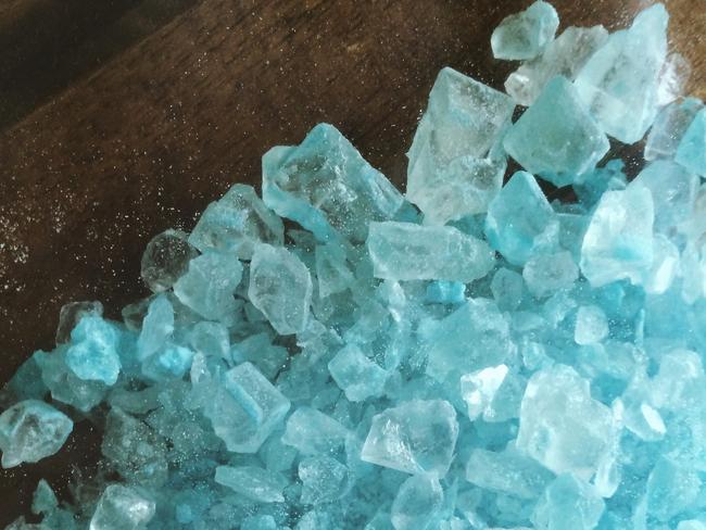 A large amount of crystal meth that has a blue color like the TV show Breaking Bad. The crystals are spilled out across a table. The image is vertical (stock image).