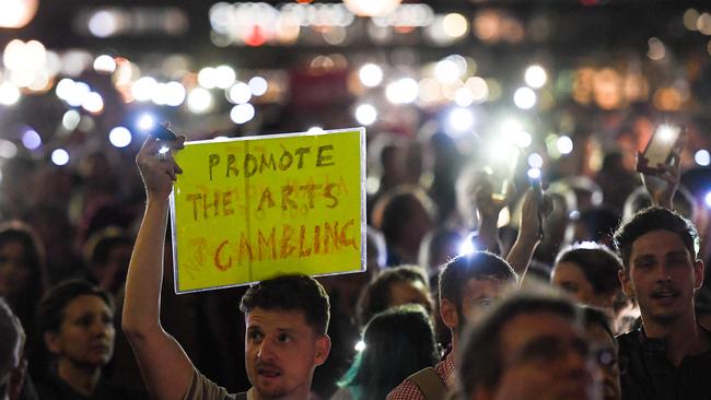 Demonstrators hold placards during a protest against the decision to project the Everest barrier draw results onto the sails of the Opera House. Picture: AAP Image/Paul Braven