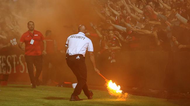 Security staff remove a flare during Friday night’s derby. Picture: AAP