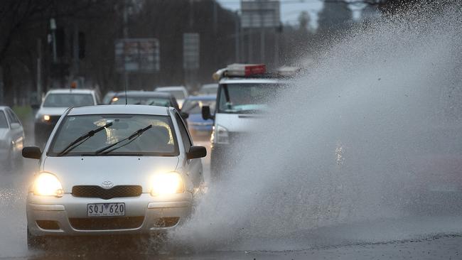 Cars drive through water lying on Alexandra Parade in Fitzroy North. Picture: Nicole Garmston