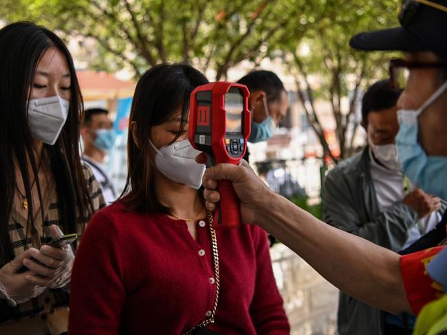 Passengers have their body temperatures and a health code on their phones checked before they take a taxi after arriving at Hankou railway station in Wuhan. Picture: AFP