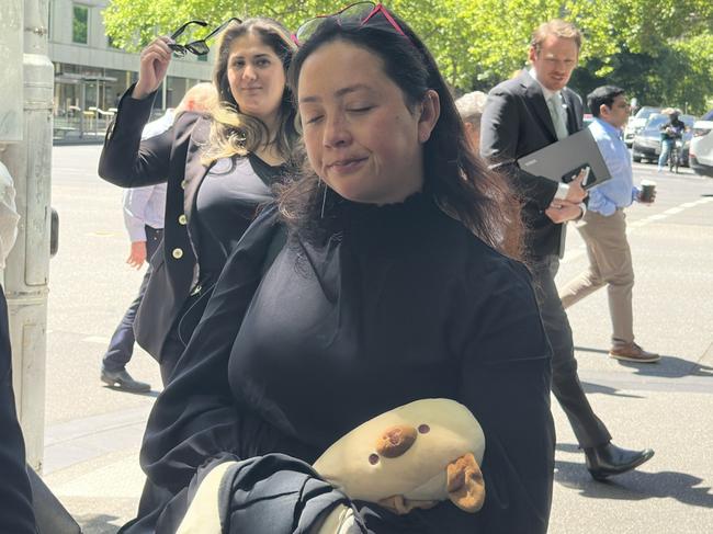 Victoria Police adviser Caitlin Schiavone (holding a white stuffed toy) leavesthe Melbourne Magistrates Court.Picture: Mohammad Alfares