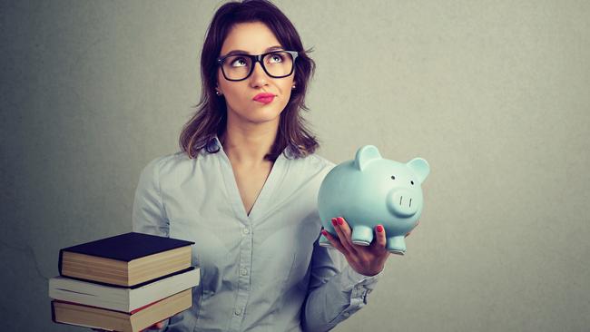 Student loan concept. Young woman with pile of books and piggy bank full of debt rethinking future career path