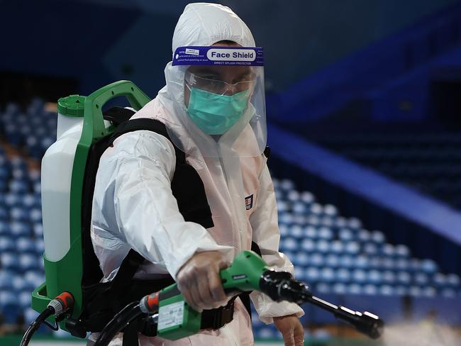 A staff member in PPE sanitises equipment and signage boards following after the Giants’ clash with West Coast Fever. Picture: Getty Images