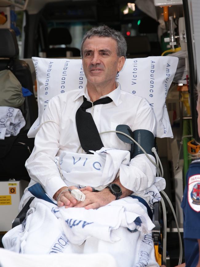 Terry McMaster being loaded into the back of an ambulance after collapsing in the stand at the banking royal commission. Picture: Stefan Postles