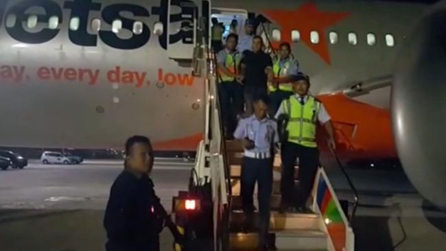 One of the men are removed from the Jetstar flight after it arrived in Bali.