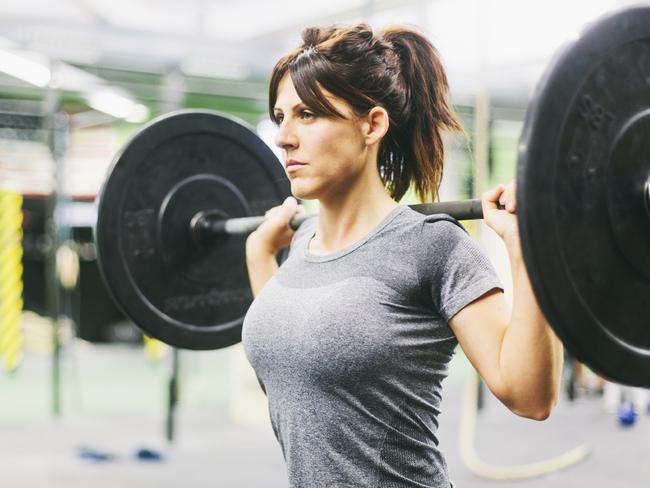 One young woman working hard in the gym. More files of this series on port. She is lifting weights. Sport and fitness.